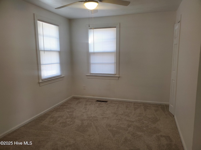 unfurnished room featuring carpet floors, visible vents, baseboards, and a ceiling fan