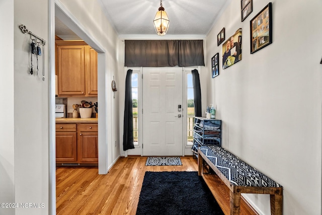 entryway with ornamental molding and light wood finished floors