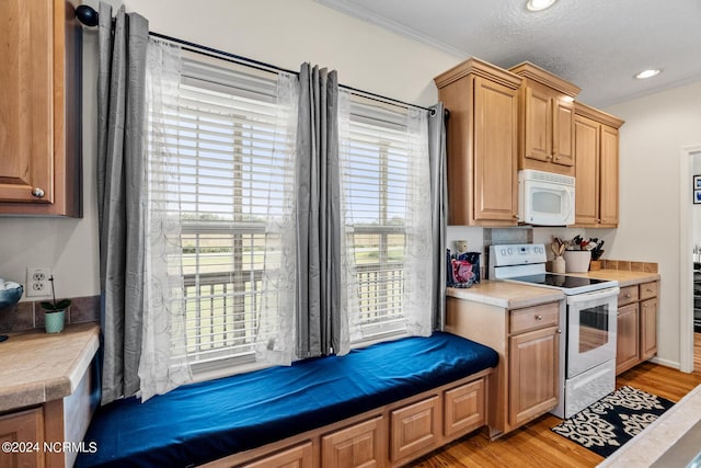 kitchen featuring recessed lighting, light countertops, light wood-style flooring, ornamental molding, and white appliances