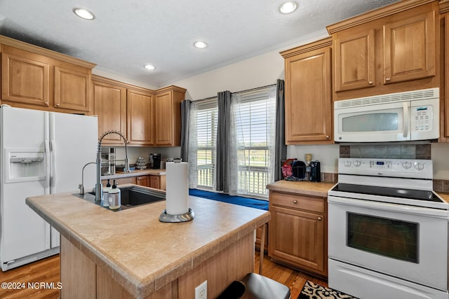 kitchen with white appliances, a center island with sink, light wood finished floors, and a sink