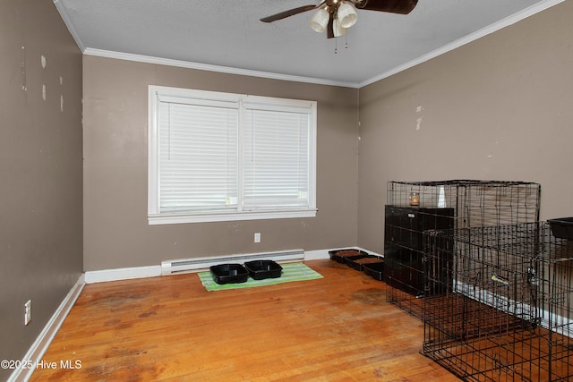 miscellaneous room with a baseboard heating unit, wood finished floors, crown molding, baseboards, and ceiling fan