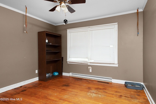 spare room featuring wood finished floors, baseboards, a baseboard radiator, ceiling fan, and crown molding