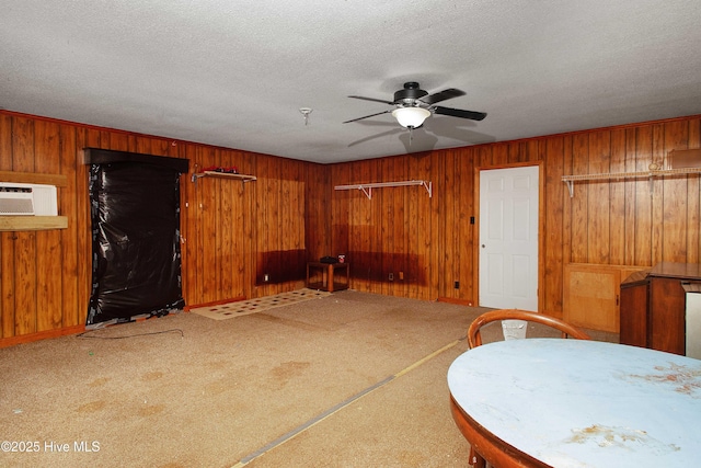 dining space with a textured ceiling, ceiling fan, wood walls, and carpet