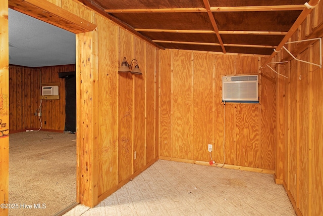 carpeted spare room featuring wooden walls and a wall unit AC