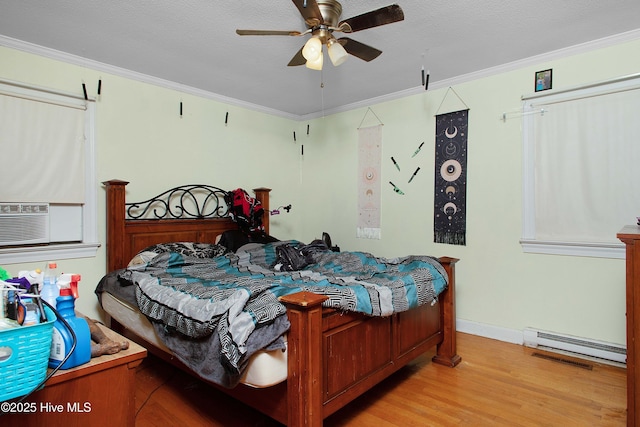 bedroom featuring wood finished floors, baseboard heating, ornamental molding, and a textured ceiling