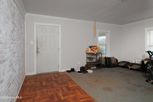 foyer with crown molding and brick wall