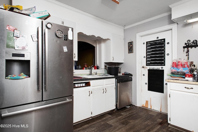 kitchen featuring dark wood-type flooring, ornamental molding, a sink, appliances with stainless steel finishes, and white cabinets