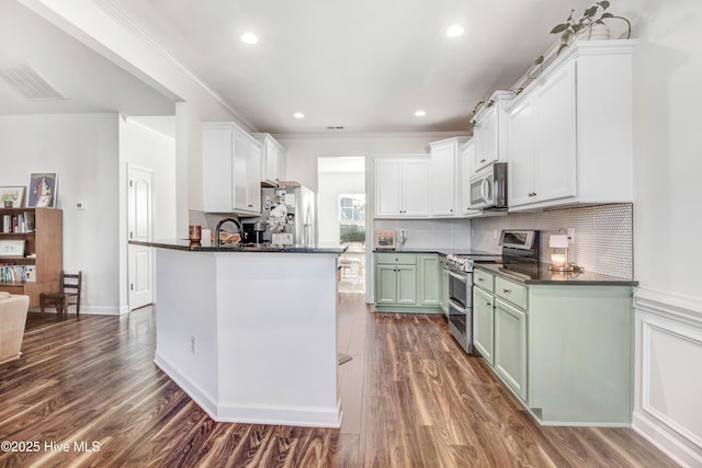 kitchen with dark wood-style floors, stainless steel appliances, dark countertops, and visible vents