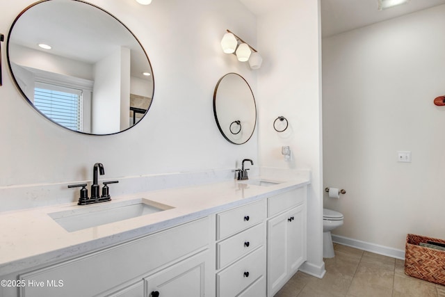 bathroom featuring double vanity, baseboards, toilet, and a sink