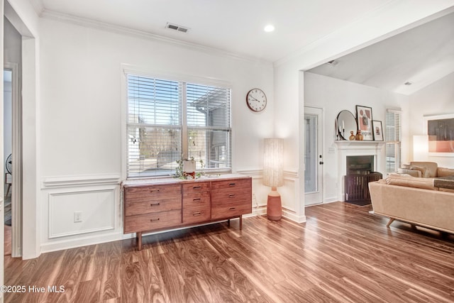 living area featuring crown molding, dark wood-style flooring, visible vents, and a fireplace