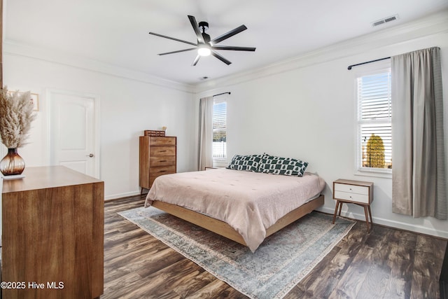 bedroom with dark wood-style flooring, visible vents, crown molding, and baseboards