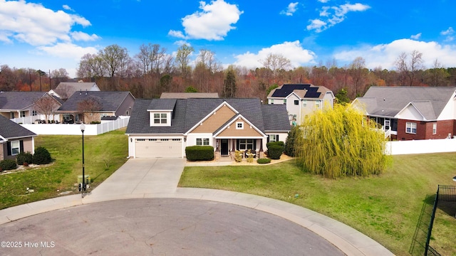 view of front of home with a porch, fence, concrete driveway, a residential view, and a front yard