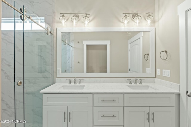 full bath with double vanity, a sink, and a marble finish shower