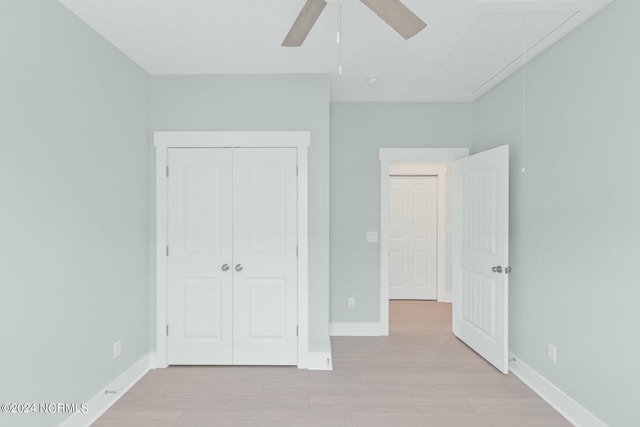 unfurnished bedroom with attic access, a closet, light wood-style floors, and baseboards