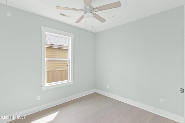 unfurnished room featuring ceiling fan, wood finished floors, visible vents, and baseboards