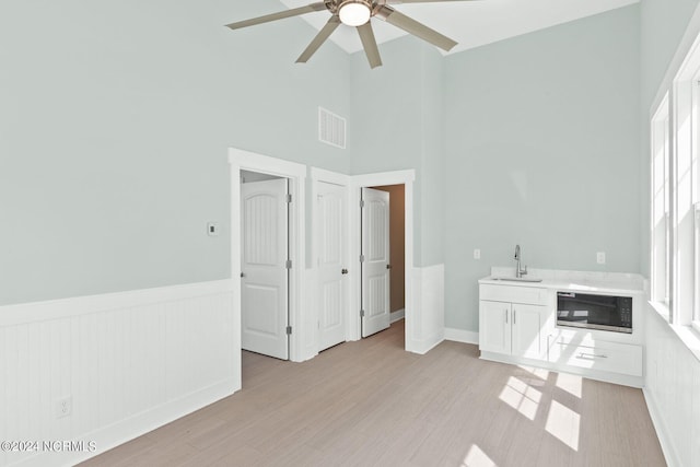 interior space featuring light wood-type flooring, a wainscoted wall, visible vents, and a sink