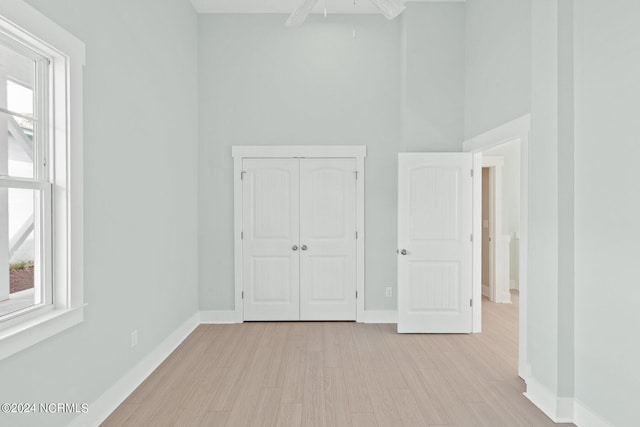 unfurnished bedroom with light wood-style floors, a closet, and baseboards