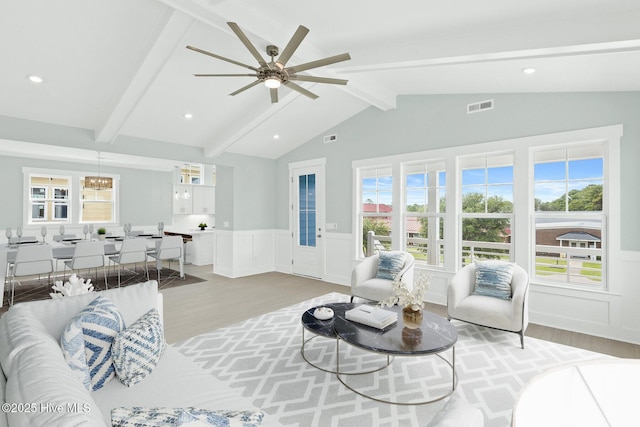 living area featuring vaulted ceiling with beams, recessed lighting, visible vents, light wood-type flooring, and wainscoting