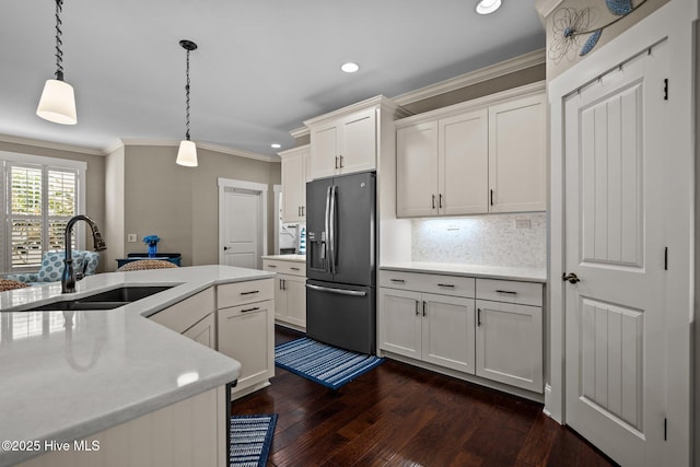 kitchen with crown molding, light countertops, a sink, and stainless steel fridge with ice dispenser