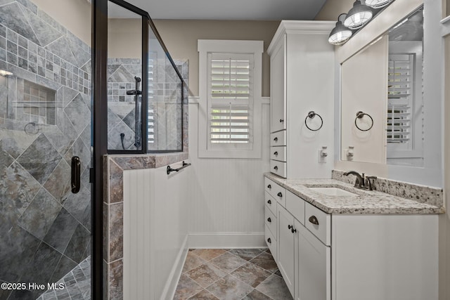 bathroom with a shower stall, baseboards, and vanity