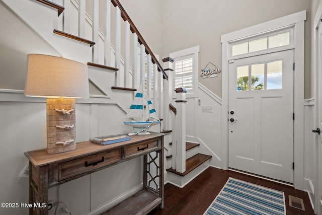 entryway with stairs, dark wood-type flooring, and visible vents