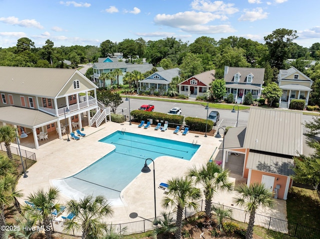 community pool with a patio, fence, and a residential view