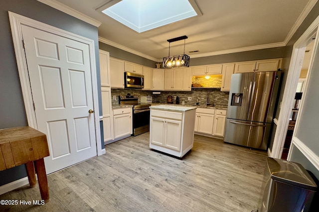 kitchen featuring stainless steel appliances, a skylight, a sink, light wood-style floors, and ornamental molding