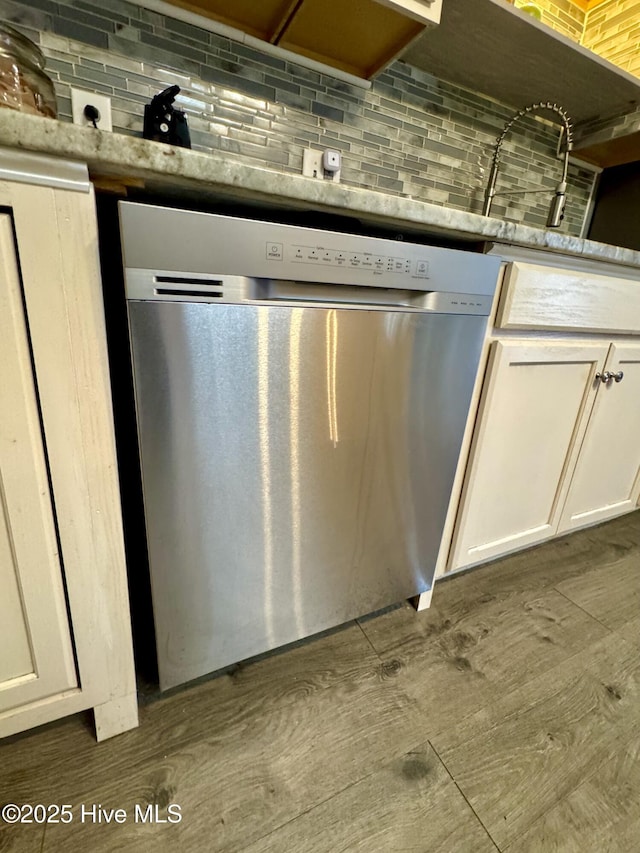 room details with dark wood-type flooring, white cabinetry, stainless steel dishwasher, and tasteful backsplash