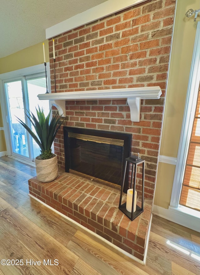 details with a textured ceiling, a fireplace, and wood finished floors