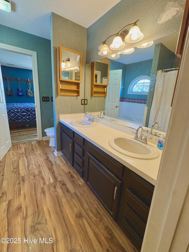 ensuite bathroom featuring a sink, toilet, and double vanity