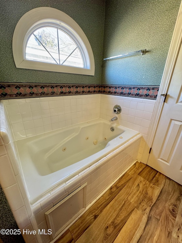 bathroom with a jetted tub, wood finished floors, and wallpapered walls