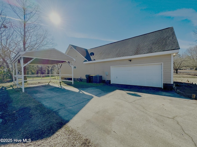 exterior space with central air condition unit, a shingled roof, and a garage