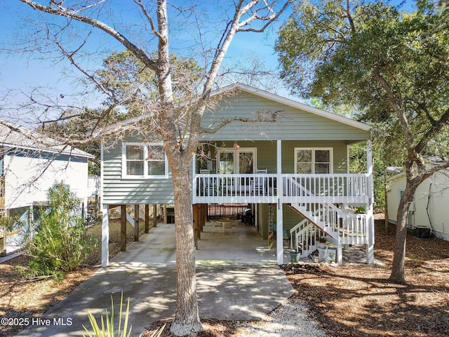 coastal inspired home featuring a porch, driveway, stairway, and a carport