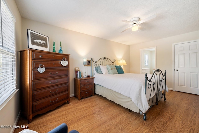 bedroom with light wood-style floors, ceiling fan, and baseboards
