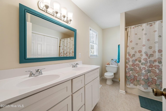 bathroom with baseboards, a sink, toilet, and double vanity