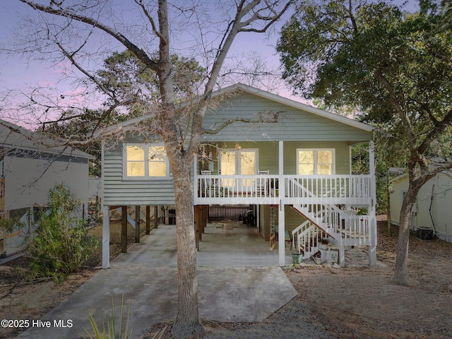 beach home with stairway, a porch, a carport, and concrete driveway