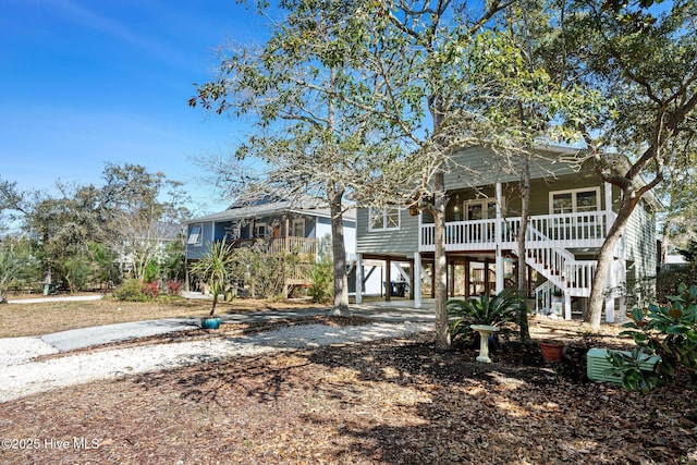 coastal home featuring a porch, stairway, driveway, and a carport