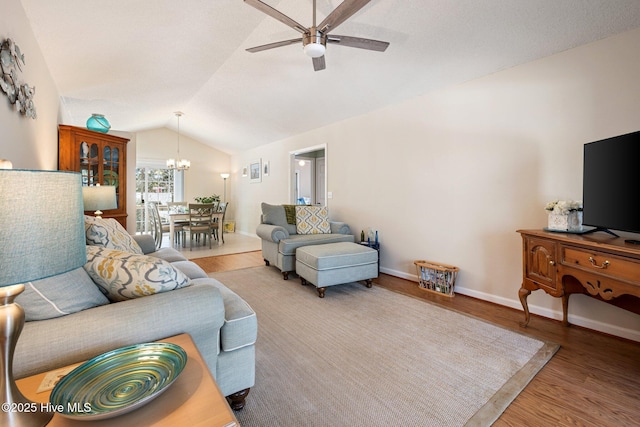 living area with baseboards, vaulted ceiling, wood finished floors, and ceiling fan with notable chandelier