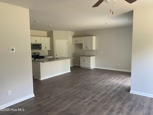 kitchen with baseboards, appliances with stainless steel finishes, white cabinets, and dark wood finished floors