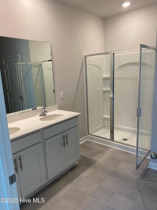 bathroom featuring double vanity, a sink, and a shower stall