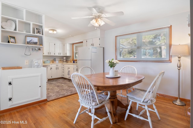 dining room featuring light wood-style flooring, baseboards, and a ceiling fan