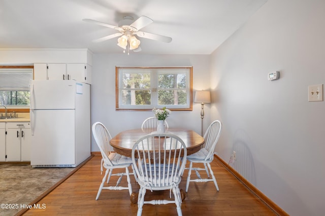 dining room with light wood finished floors, ceiling fan, and baseboards