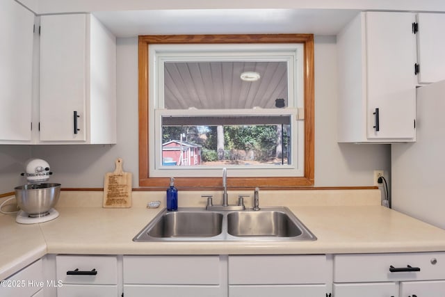 kitchen with white cabinetry, light countertops, and a sink