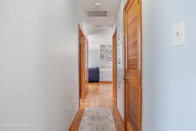 hallway featuring light wood finished floors and visible vents