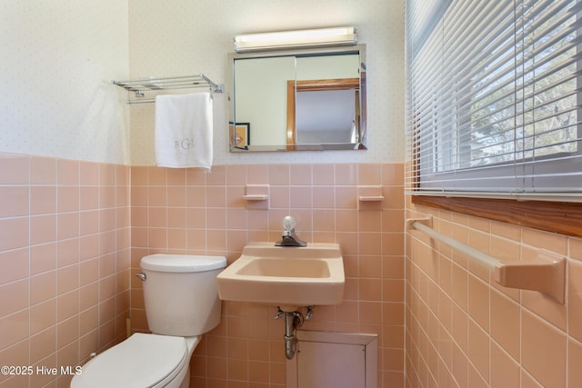 bathroom featuring toilet, a wainscoted wall, a sink, a wall mounted AC, and wallpapered walls