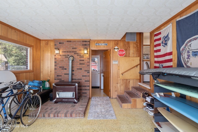 interior space featuring a wood stove, an ornate ceiling, wooden walls, and visible vents