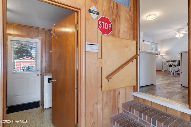 stairway with ceiling fan, speckled floor, and wooden walls