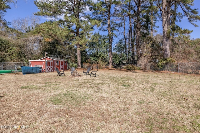 view of yard with a storage shed, fence, and an outbuilding