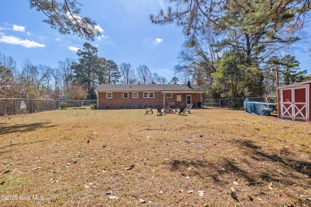 back of property with an outbuilding, a fenced backyard, crawl space, a lawn, and a shed