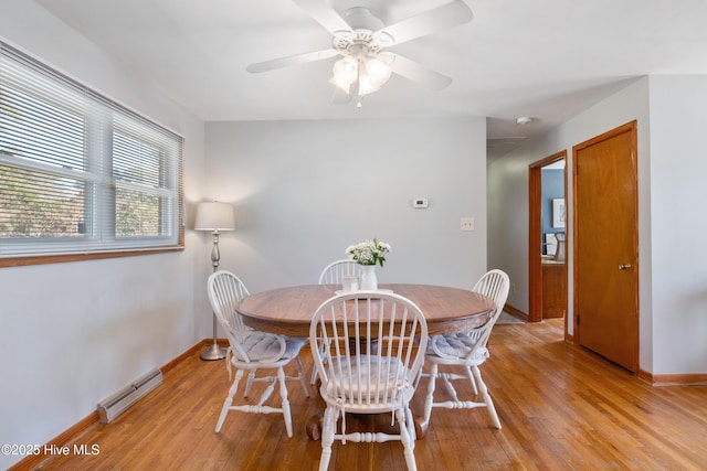 dining area with a baseboard heating unit, ceiling fan, baseboards, and light wood-style floors